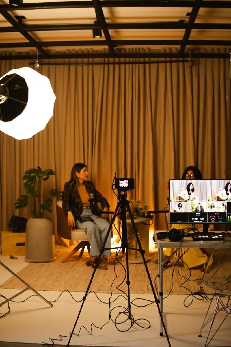 Bastidores: set de entrevista com duas cadeiras, refletor, câmera em tripé e monitor de operação