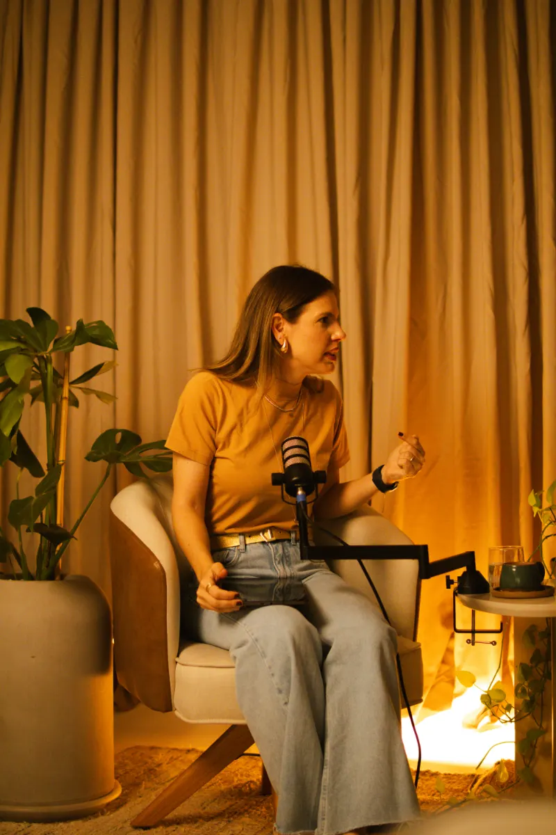 Bastidores: convidada em conversa ao microfone, sob luz quente