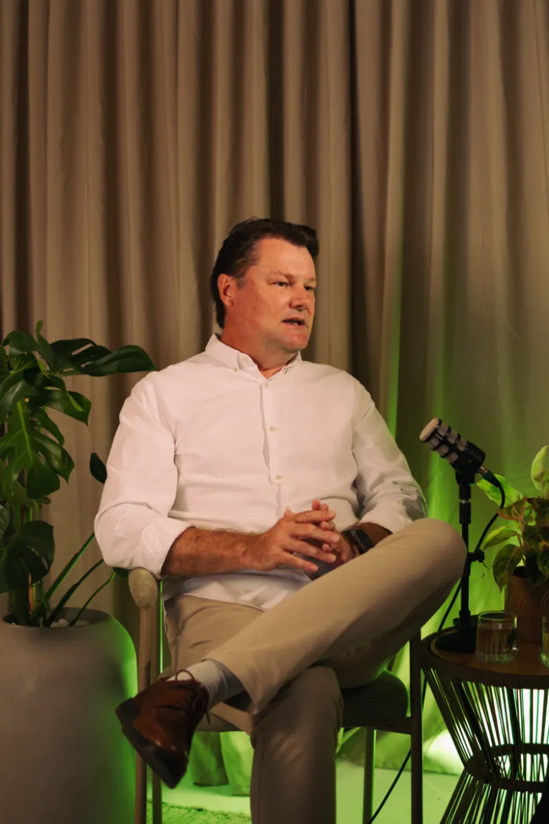 Bastidores: entrevistado de camisa branca sentado ao microfone, com luz verde ao fundo