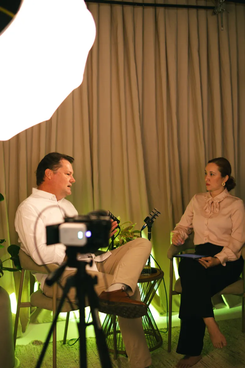Bastidores: entrevista em duas cadeiras, com a câmera em primeiro plano e o refletor ao alto