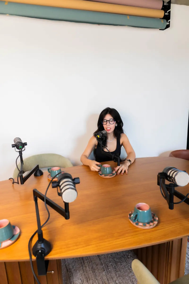 Cenário Mesa de reunião: mesa de madeira com microfones articulados e xícaras, sob fundo branco